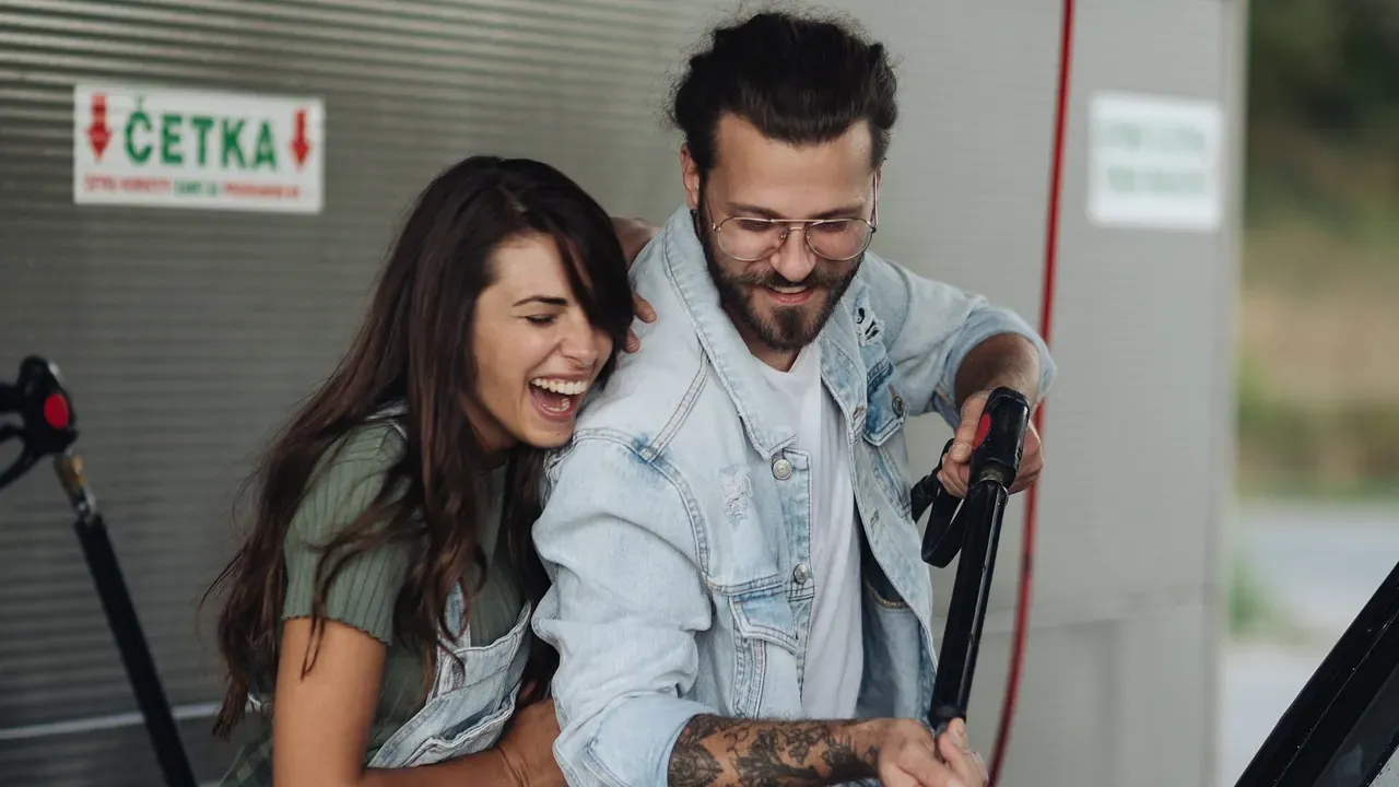 A couple examining a car-care tool beside a vehicle