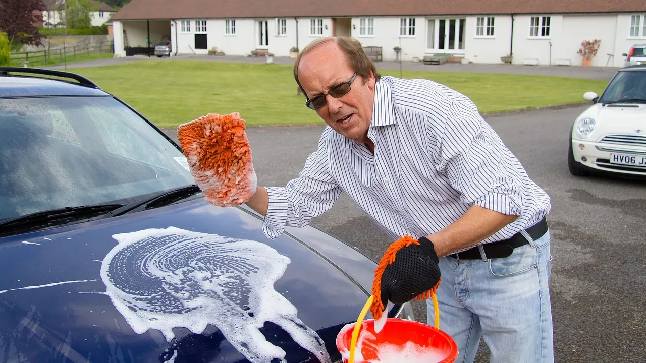 A man wiping a car hood during a community car wash