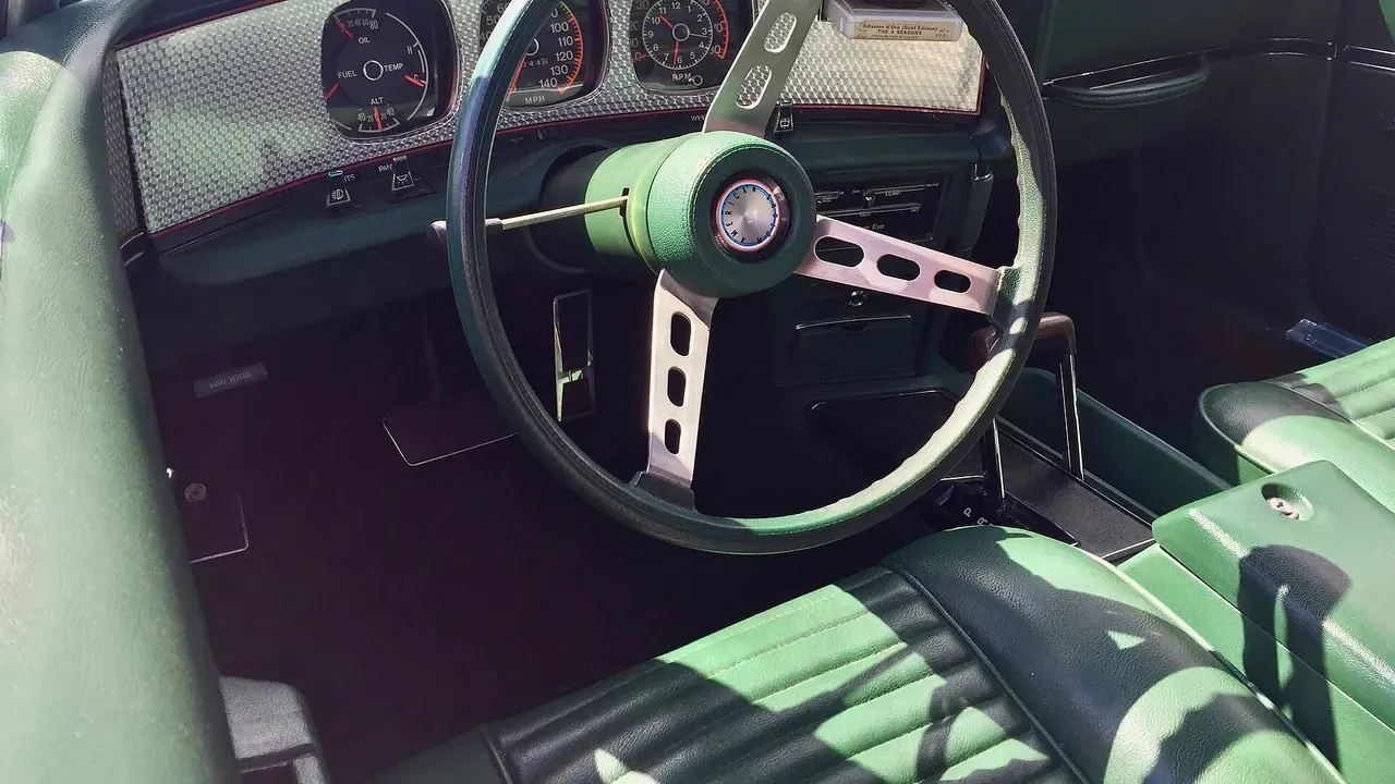 A classic car cockpit with a black steering wheel and dashboard