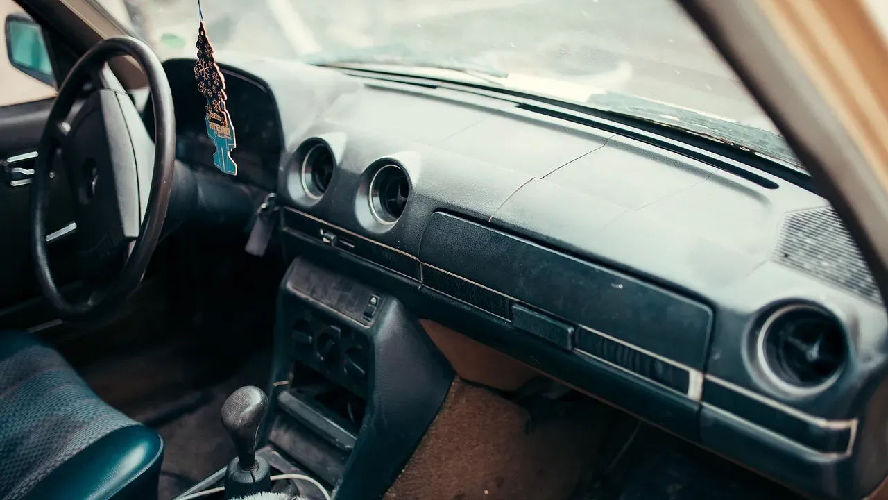 The worn dashboard and front seats of an older car