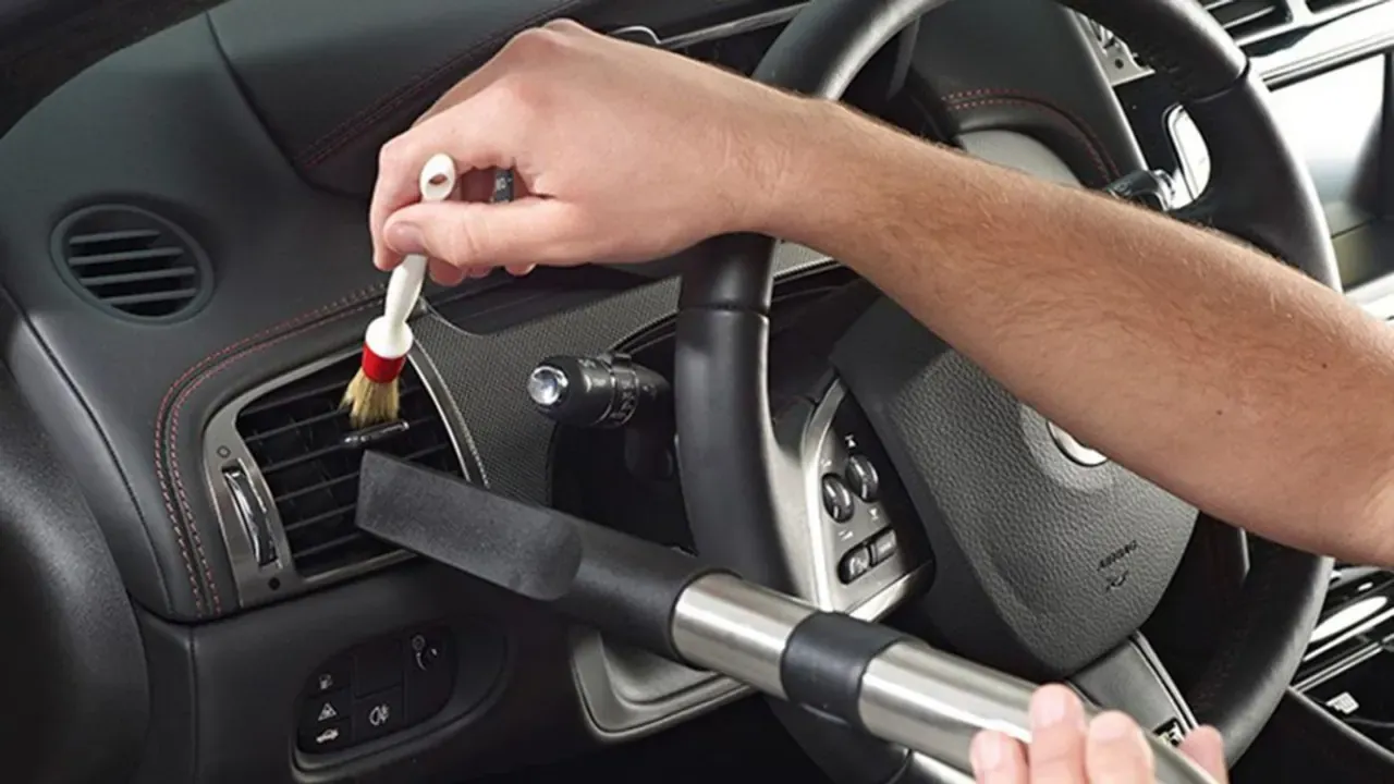 A person brushing dust from a car steering wheel