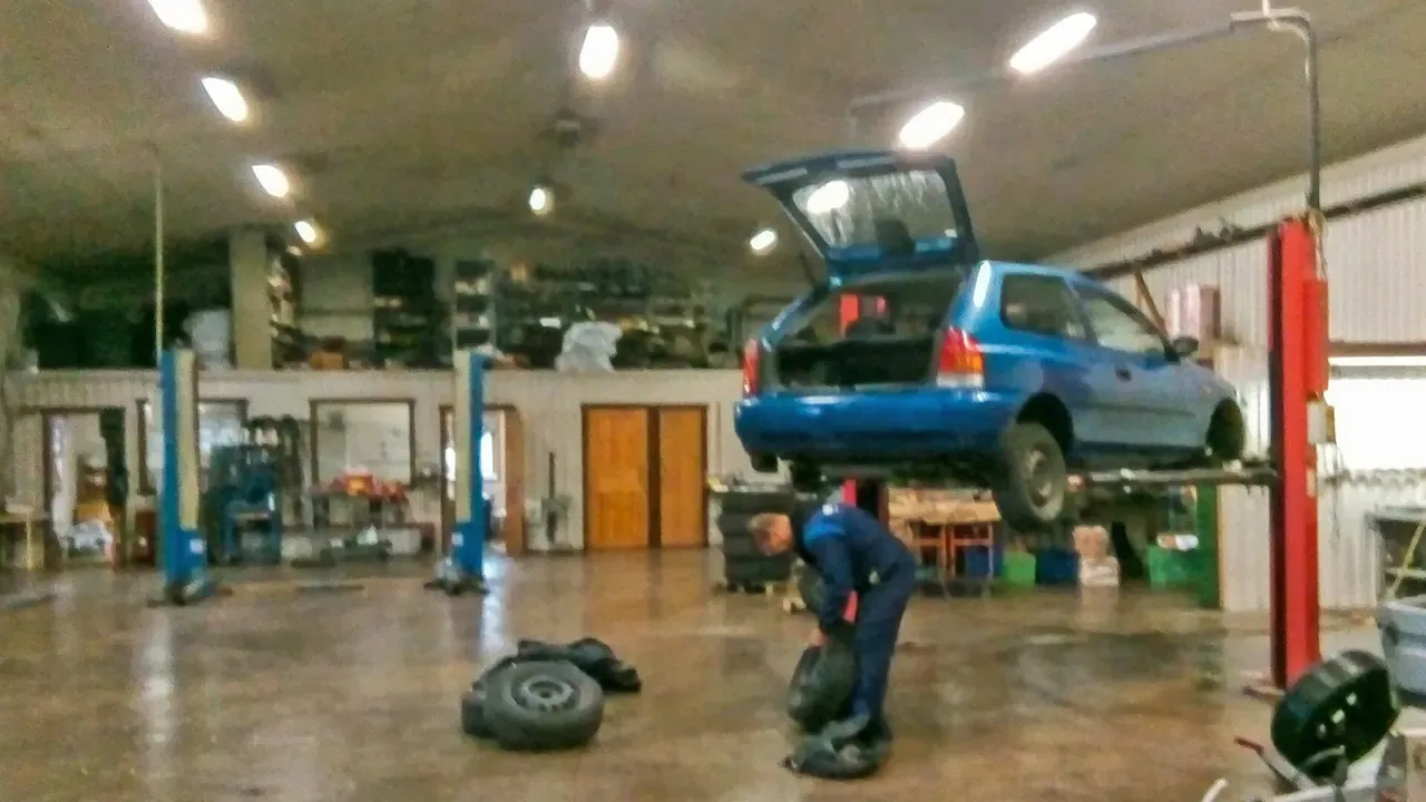 Vehicles, lifts, and tools inside a working repair garage