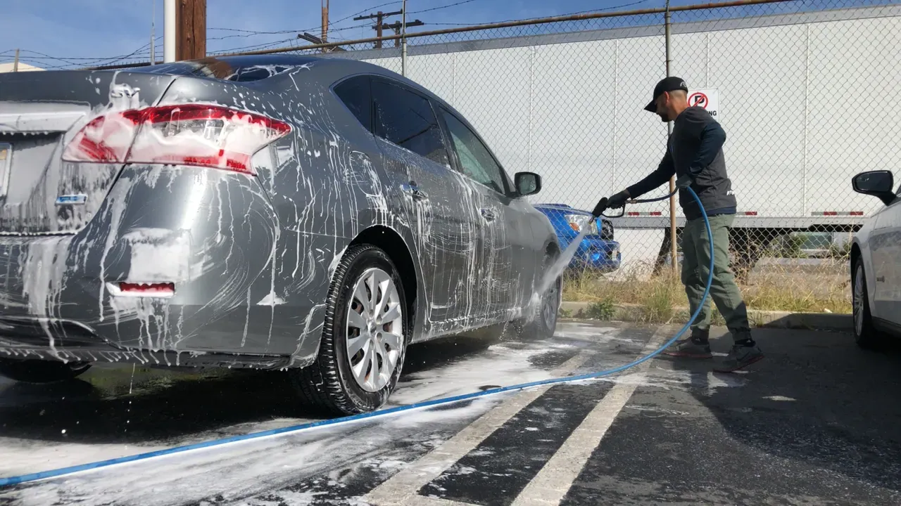 A car covered in white foam at an outdoor wash bay