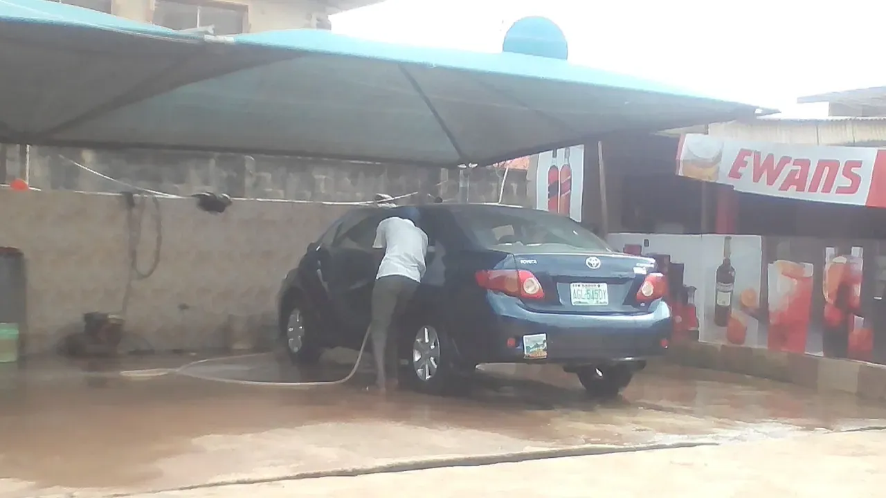 A car being rinsed with water at an outdoor wash bay