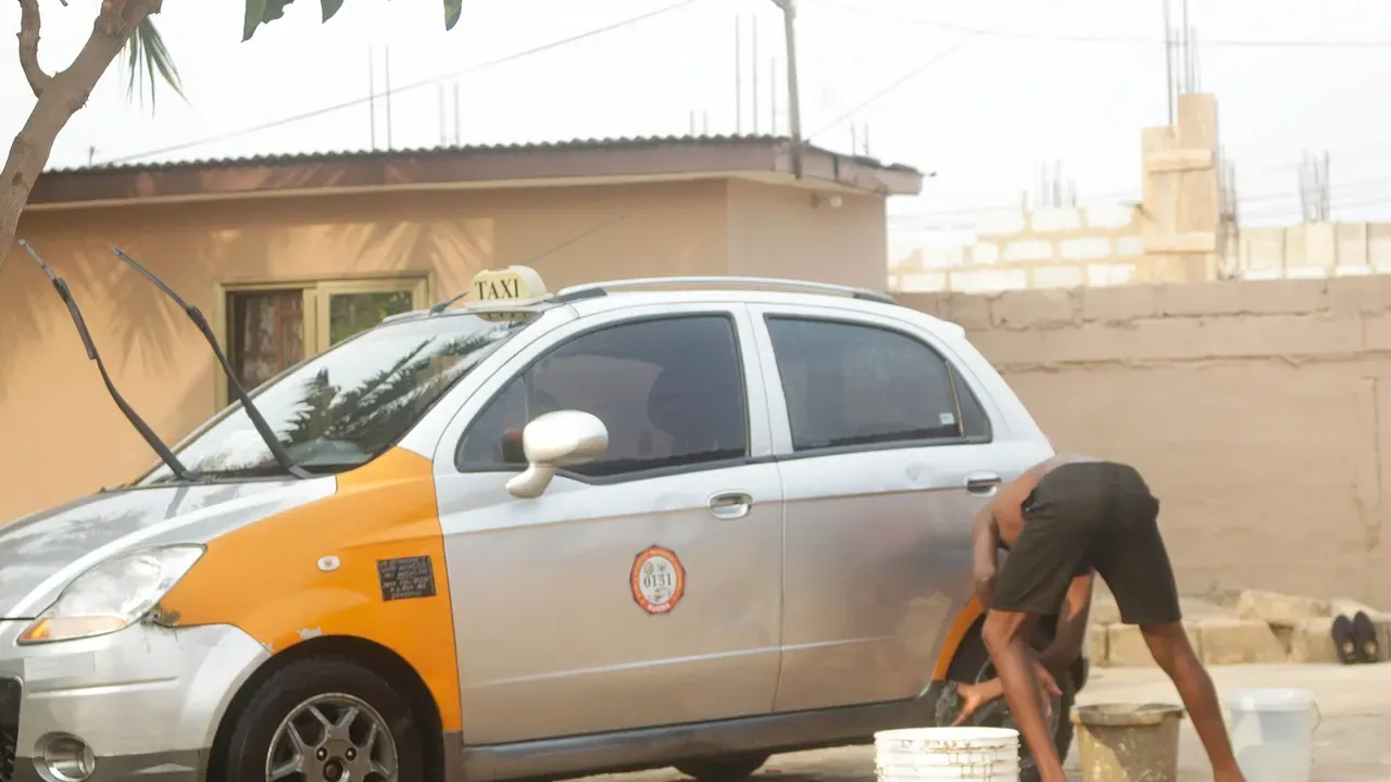 A person washing the side of a white car outdoors