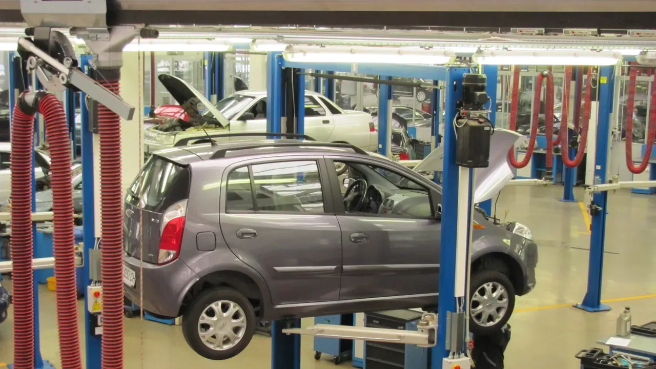 A compact car raised on a lift inside a service shop